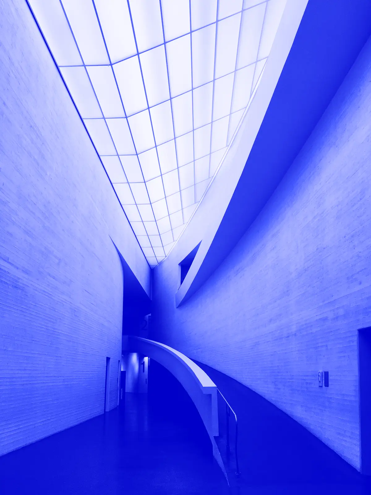 Couloir blanc courbe baigné de lumière, en duotone bleu