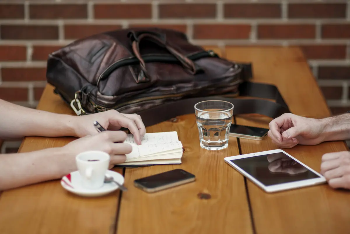 Un rendez-vous de travail autour d’une table, carnets et tablette